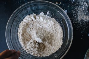 oat flour, cornstarch, cinnamon, baking powder and salt being whisked in a bowl