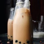 earl grey milk tea with boba pearls in a glass milk bottle