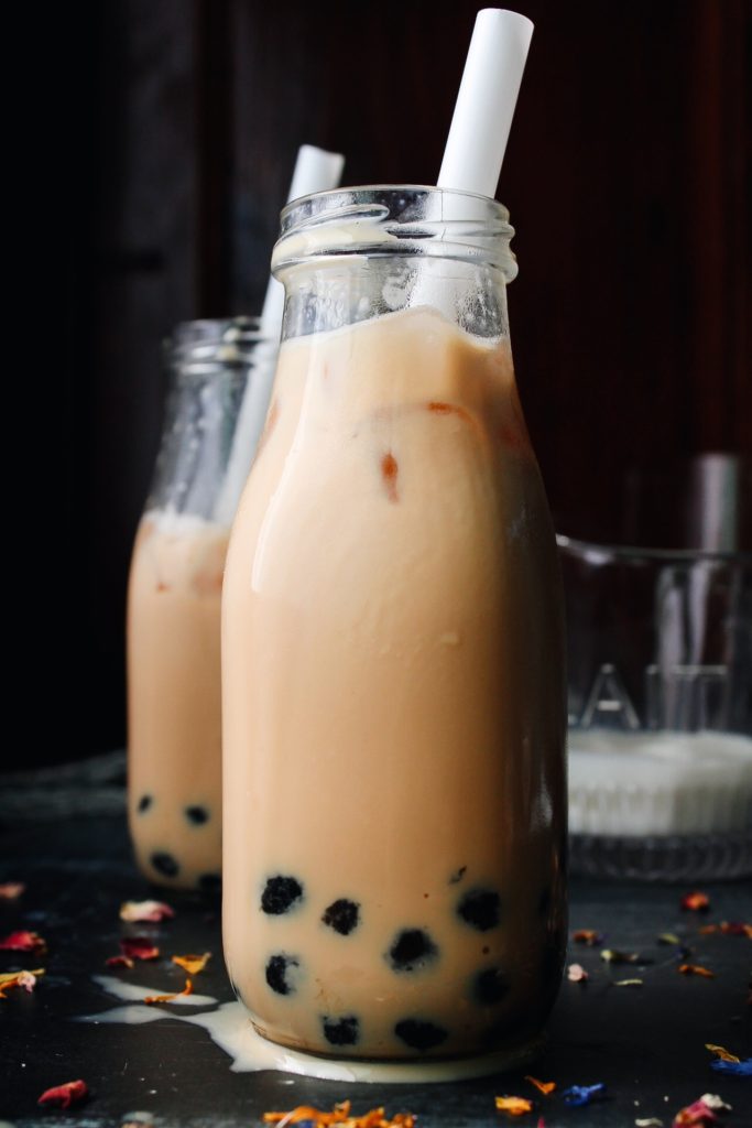 earl grey milk tea with boba pearls in a glass milk bottle