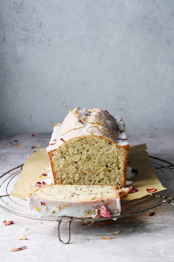 sliced loaf cake on cooling rack with dried edible flowers scattered around