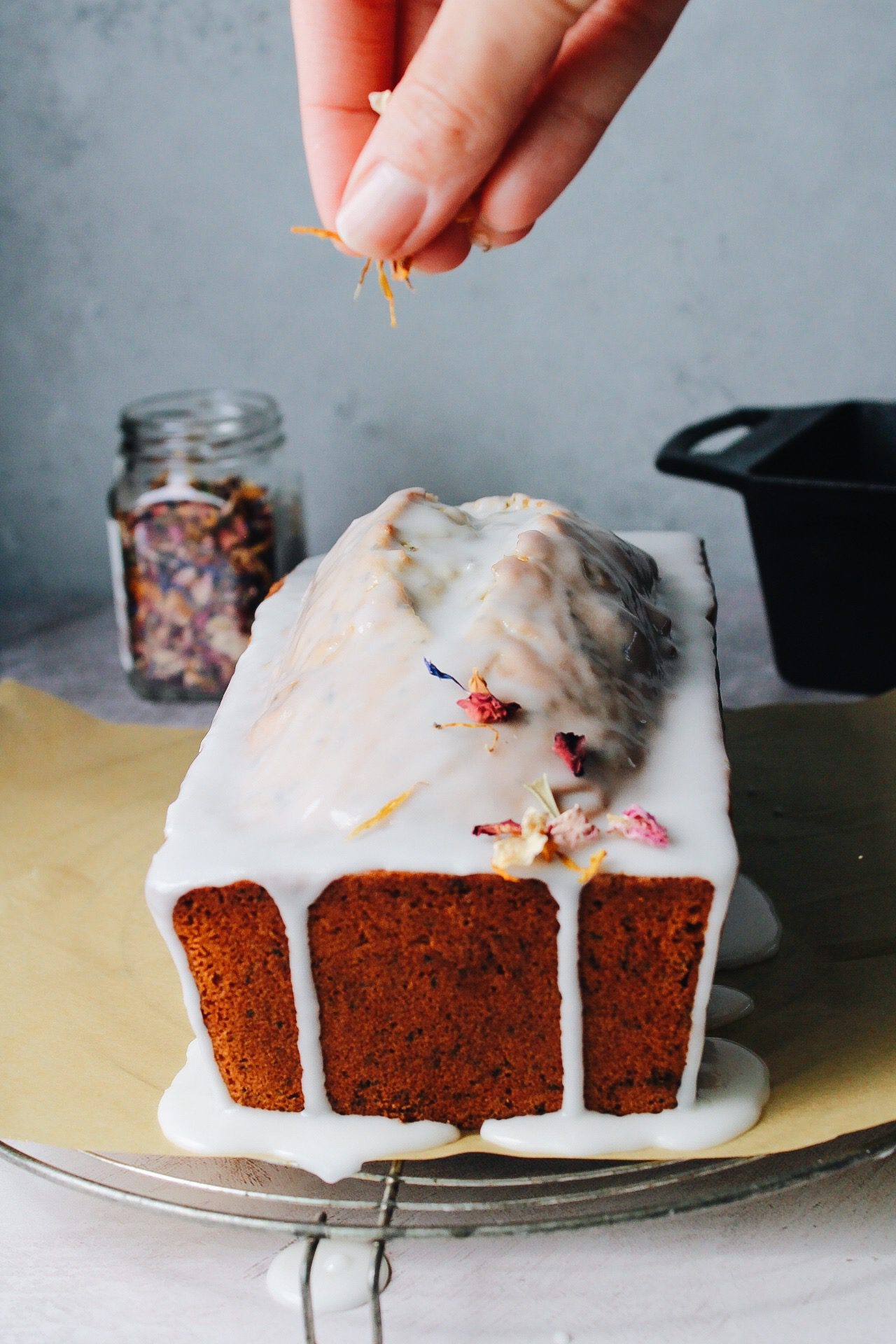 edible flowers being sprinkled on top of earl grey pound cake