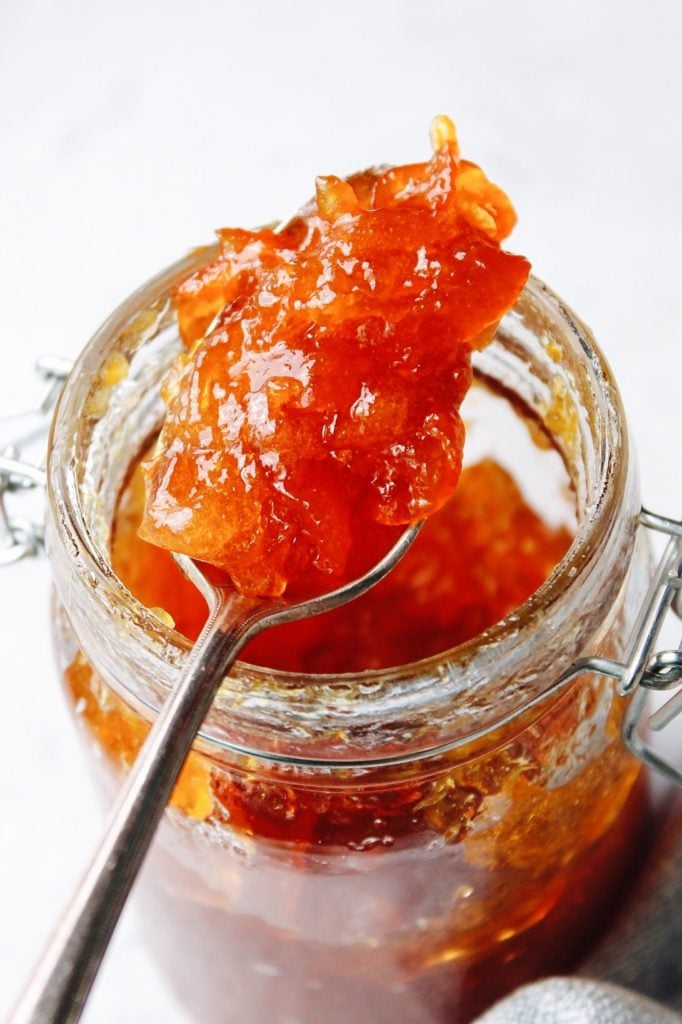 spoon with kumquat jam on a spoon resting on the jar of jam