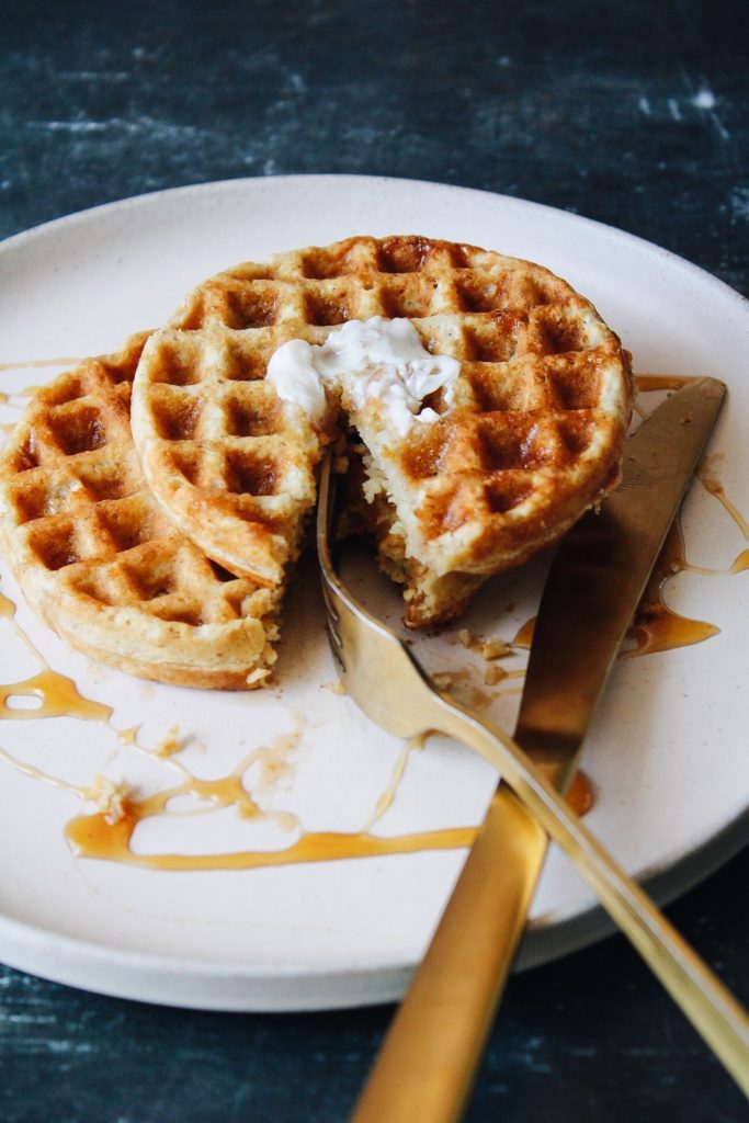 front shot of oat flour waffles on a plate with butter and syrup
