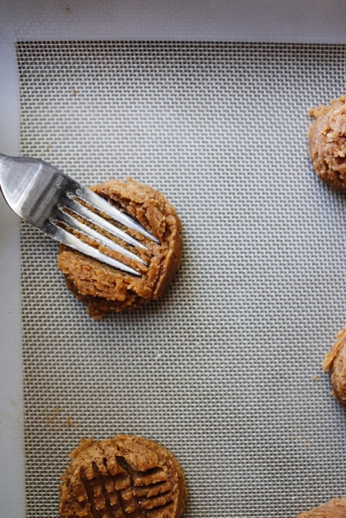 fork pressing into peanut butter cookie dough to make cross hatch pattern