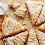 roasted kumquat scones on a baking sheet with a spoon of icing