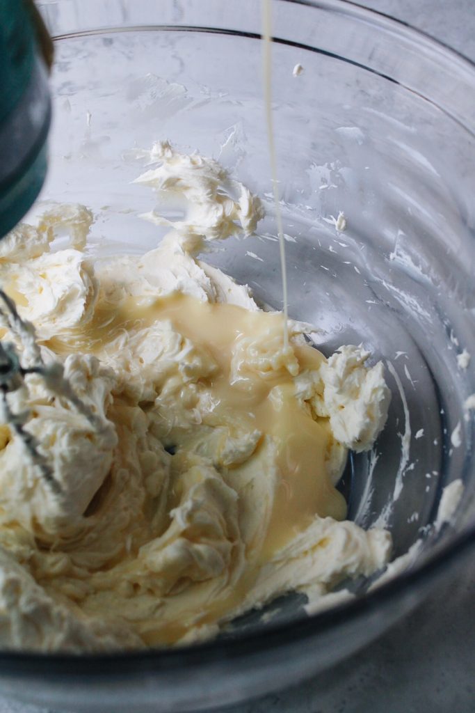 sweetened condensed milk being slowly drizzled into cream cheese