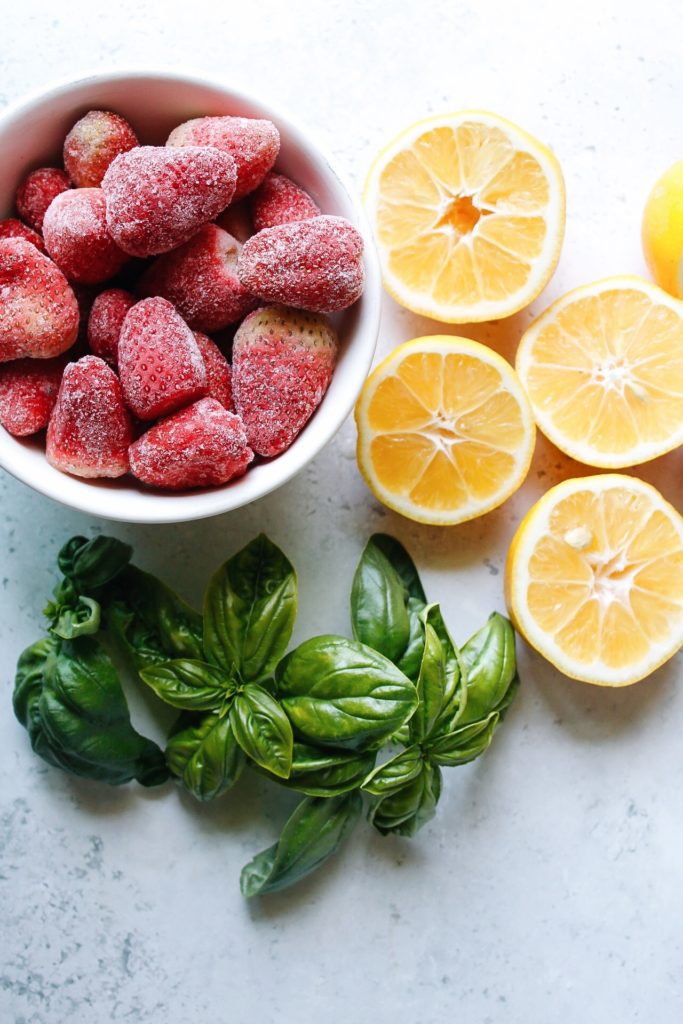 ingredients for strawberry basil lemonade: frozen strawberries, lemons, fresh basil