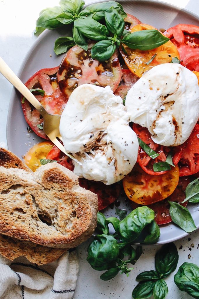 caprese salad with burrata cheese on a gray plate