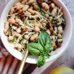 tuscan white bean salad in a white bowl topped with basil