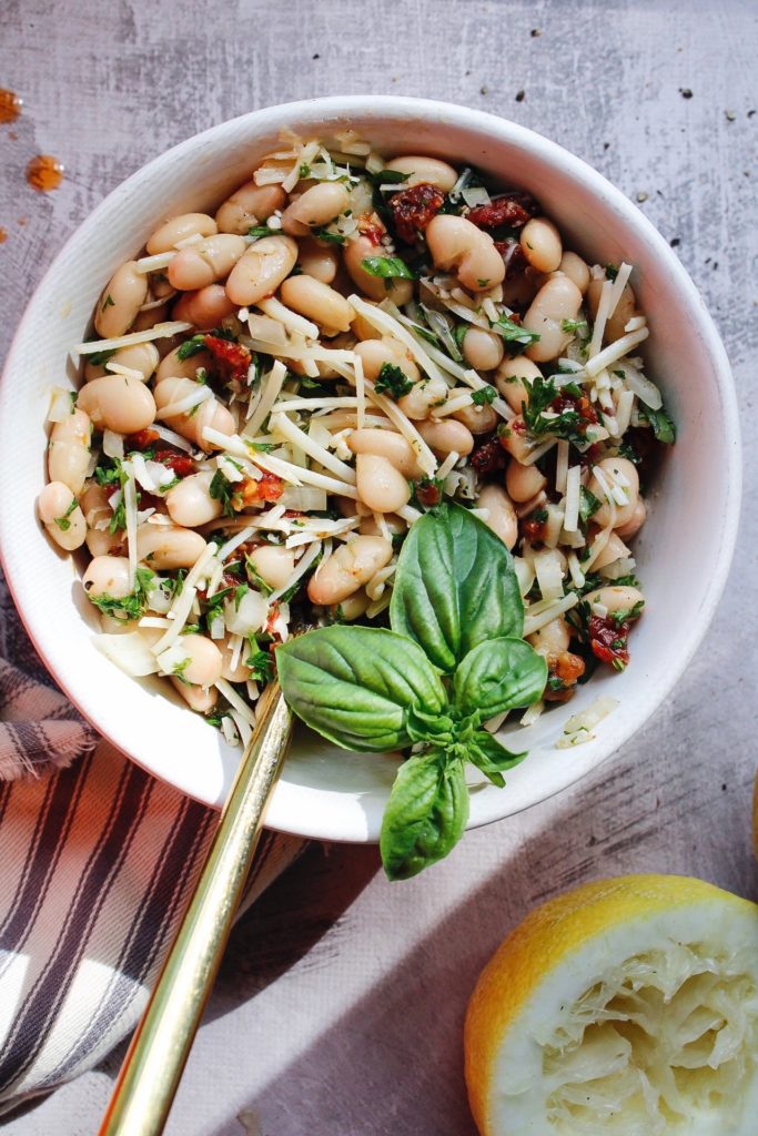 tuscan white bean salad in a white bowl topped with basil