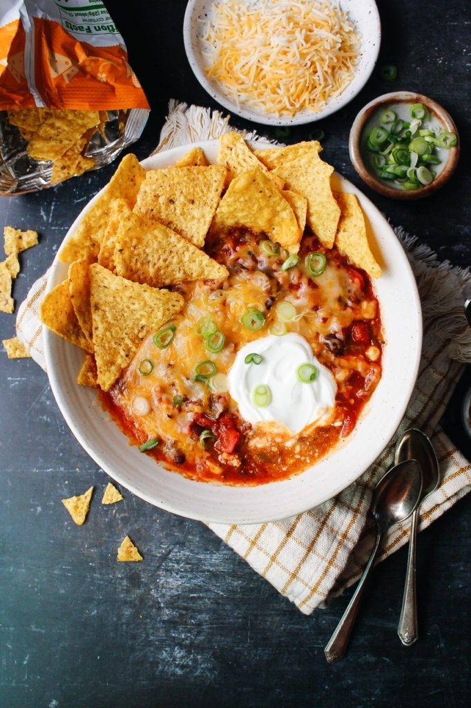 Southwest chicken chili in a white bowl with tortilla chips and sour cream