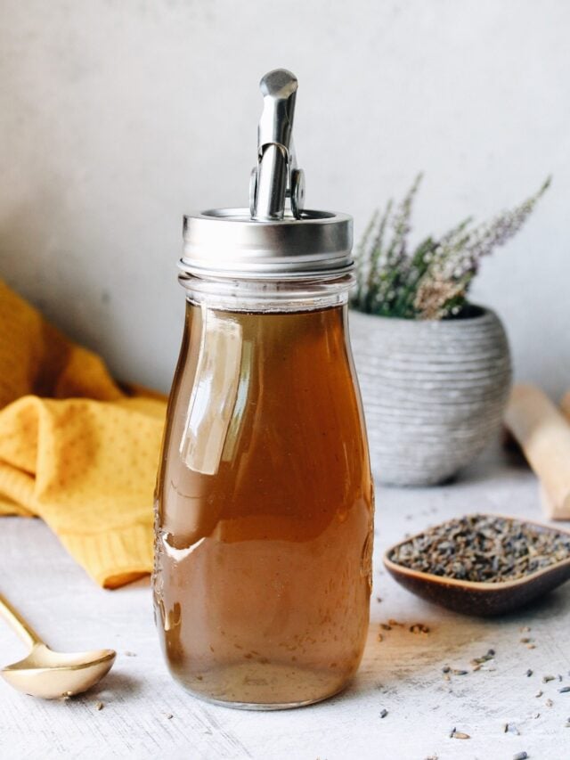 lavender simple syrup in a glass jar with a pour spout