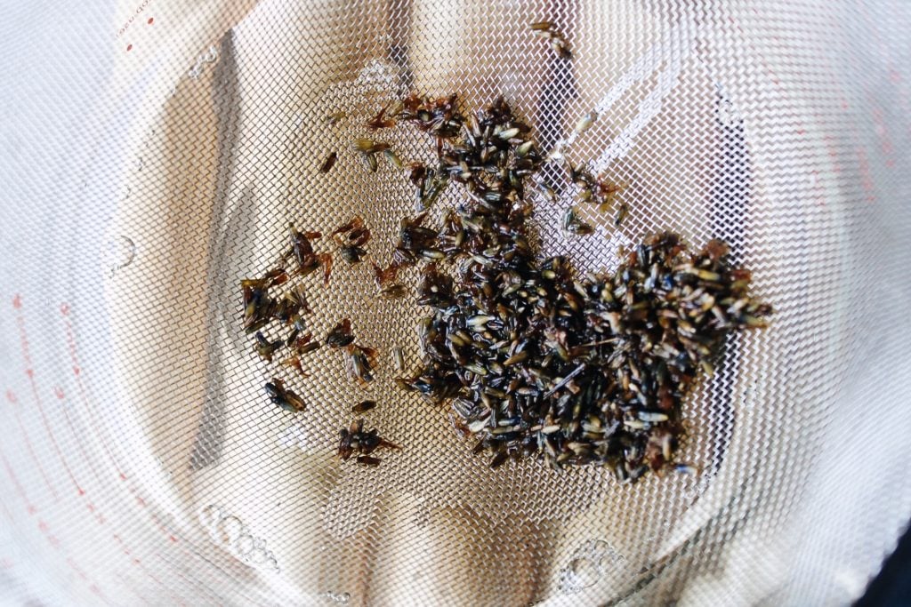 lavender flowers being strained out of simple syrup