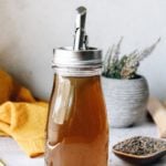 lavender simple syrup in a glass jar with a pour spout