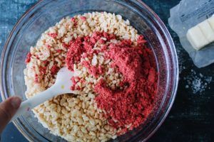 rice krispie cereal and freeze-dried strawberry powder in a large mixing bowl