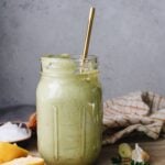 lemon herb tahini sauce in a jar surrounded by lemon, parsley, garlic