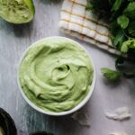 avocado cream sauce in a small white bowl surrounded by ingredients