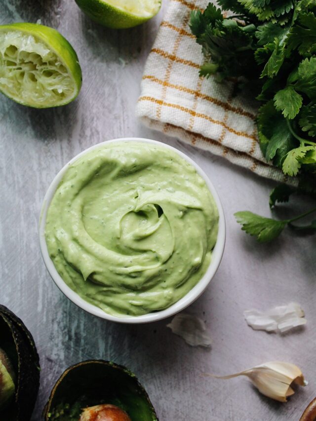 avocado cream sauce in a small white bowl surrounded by ingredients