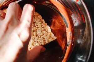 rice krispie treat getting dipped into melted chocolate