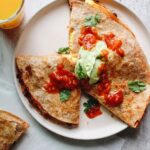 breakfast quesadillas topped with salsa and avocado creama
