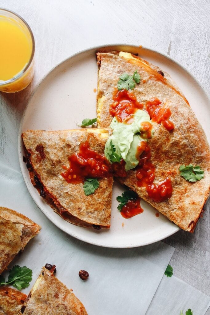 breakfast quesadillas topped with salsa and avocado creama