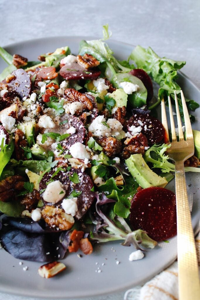 beet and avocado salad on a gray plate with a gold fork