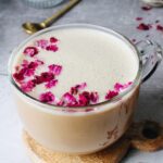 rose latte in a glass mug topped with dried rose petals