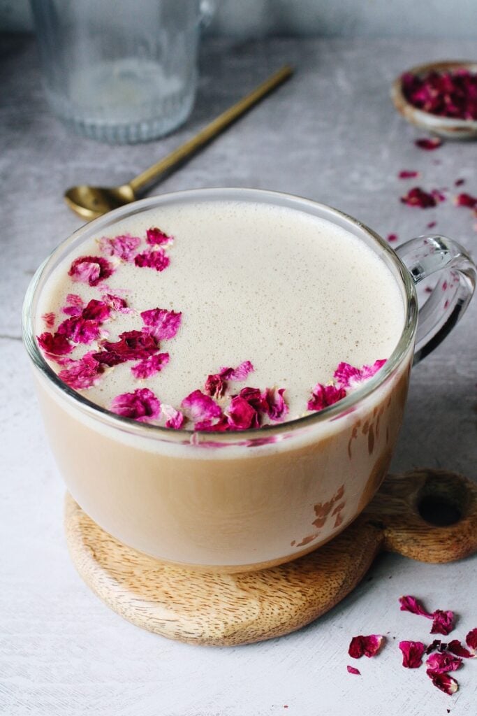 rose latte in a glass mug topped with dried rose petals