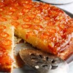 kumquat upside down cake on a gray plate with a cake server resting on the plate