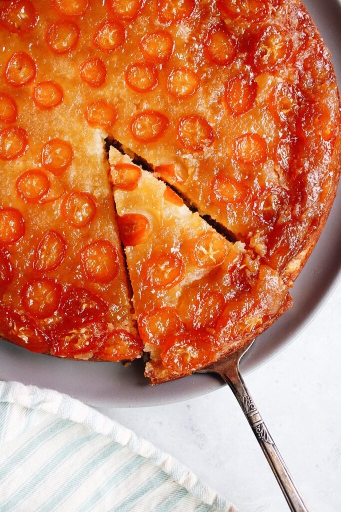 kumquat upside-down cake on a gray plate with one slice cut