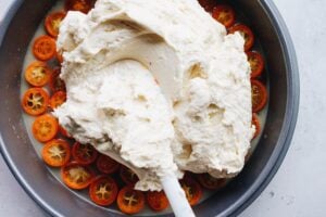 cake batter being spread in pan with kumquats and brown sugar