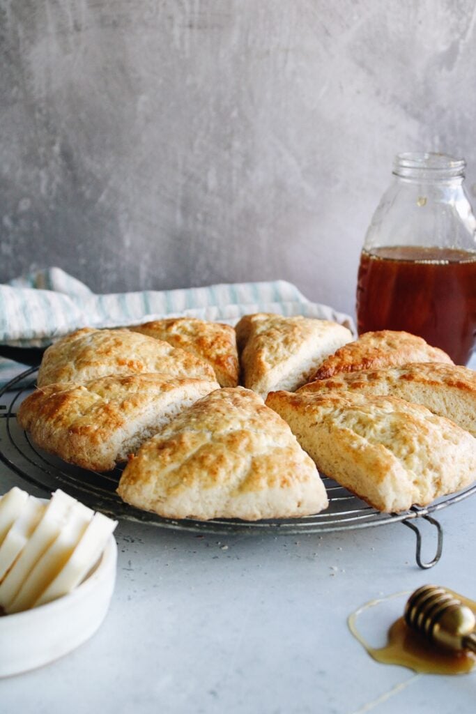 honey scones on a wire baking rack with butter in the foreground and honey in the background