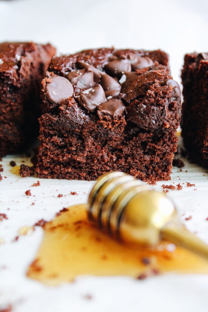 close up of honey brownies with a honey dipper in the foreground