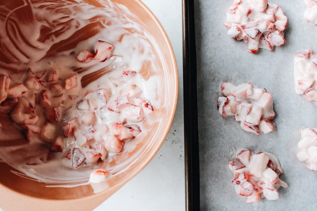 chopped strawberries mixed with yogurt and placed on parchment in clusters to freeze