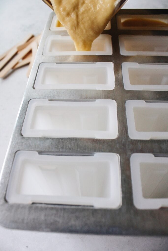 mango popsicles mixture being pour into popsicle mold