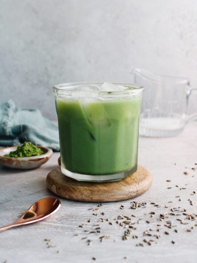 lavender matcha latte in a clear glass over ice