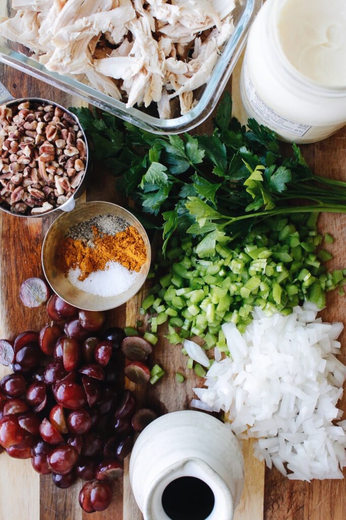ingredients for curry chicken salad with grapes on a cutting board