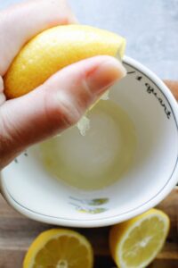 lemon being juiced into liquid measuring cup