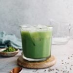 lavender matcha latte in a clear glass over ice