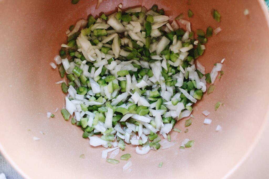 diced onion and celery in a bowl with vinegar, salt and sugar