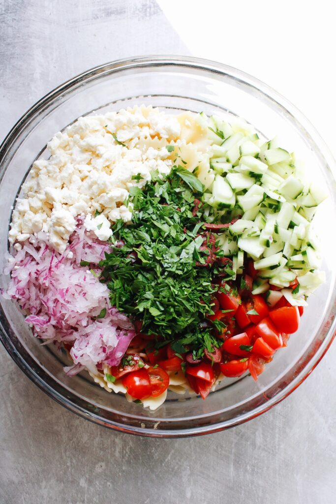 pasta salad ingredients in a bowl ready to be mixed