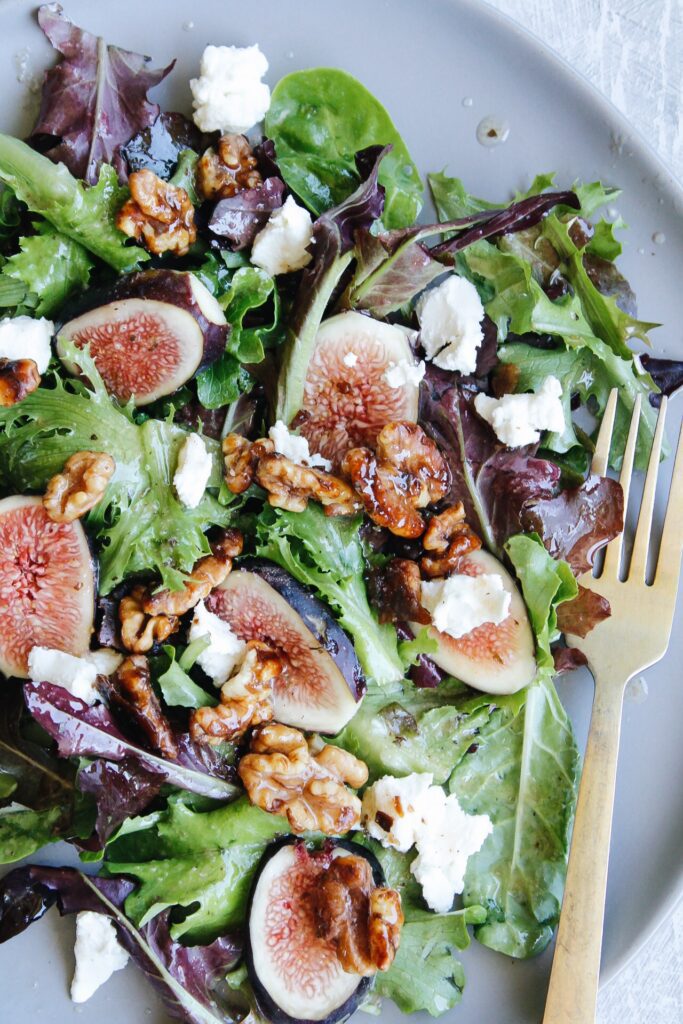 fig salad on a gray plate with a gold fork