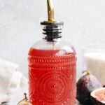 fig syrup in a glass syrup bottle with figs scattered around