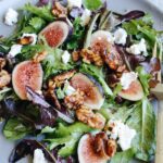 fig salad with goat cheese, candied walnuts and vinaigrette on a gray plate