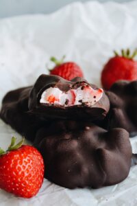 chocolate covered yogurt bites with a bite taken out of it to expose the yogurt and fruit inside