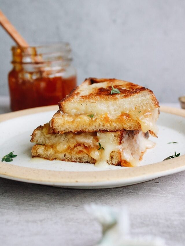 brie grilled cheese sandwich cut in half and stacked on a plate