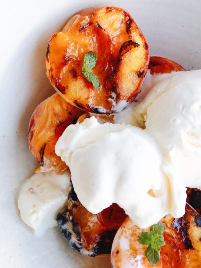 grilled peaches i na bowl topped with vanilla ice cream and mint