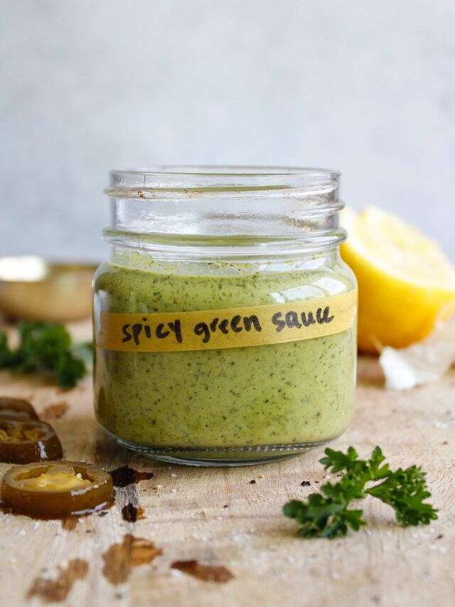 spicy green sauce in a glass jar on a wooden cutting board