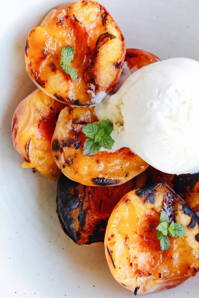 grilled peaches in w bowl with ice cream and mint