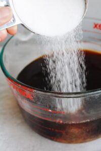 sugar being added to a batch of sweet tea